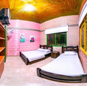 a room with three beds and a pink wall at Finca Hotel San Isidro in Hojas Anchas