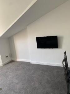 a living room with a flat screen tv on a white wall at No 9 - LARGE 1 BED NEAR SEFTON PARK AND LARK LANE in Liverpool