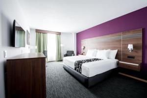 a hotel room with a large bed and a purple wall at La Quinta by Wyndham San Jose Chiapa Puebla in San Jos&eacute; Chiapa