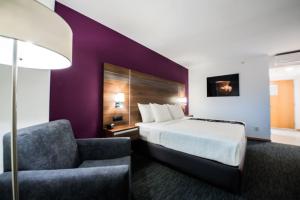 ein Hotelzimmer mit einem Bett und einem Stuhl in der Unterkunft La Quinta by Wyndham San Jose Chiapa Puebla in San José Chiapa
