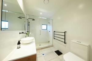 a white bathroom with a sink and a shower at Sale Street Loft in Auckland