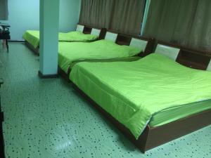 - 2 lits dans une chambre avec des draps verts dans l'établissement Navy Home Sattahib, à Sattahip