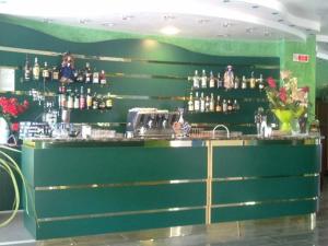 a green bar with a lot of bottles at Hotel Lily in Bibione