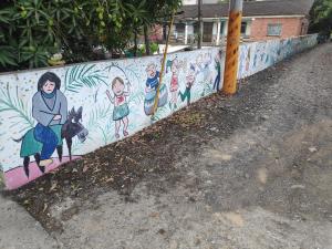 a wall with a mural of people on it at 順耆自然Shun Ci Zih Ran in Xingang