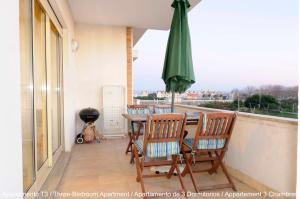 balcón con mesa, sillas y sombrilla en Apartamento Areal, en Torreira