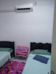 a room with two beds and a heater and a rug at Anis Homestay Kuala Perlis in Kuala Perlis