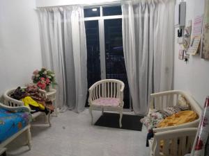 a room with two beds and two chairs and a window at Anis Homestay Kuala Perlis in Kuala Perlis