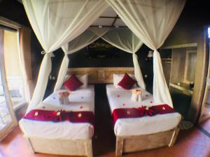 two twin beds in a room with curtains at Villa Dika Pemuteran in Pemuteran