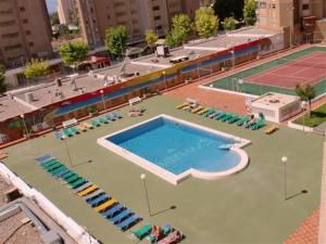 a large swimming pool with chairs and a tennis court at Apartamentos Gemelos IV - Fincas Arena in Benidorm