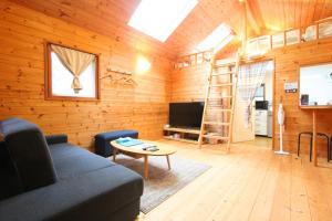 a living room with a couch and a tv at Rurikei Forest Cottage in Nantan city