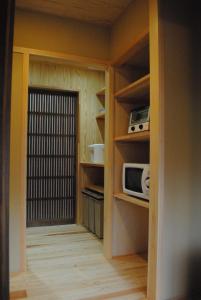 małą kuchnię z kuchenką mikrofalową i drzwiami w obiekcie NARAigoto EENA HOUSE w mieście Nara