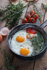 a skillet with eggs and tomatoes on a wooden table at The Condo at Palm Beach by Waiheke Unlimited in Palm Beach