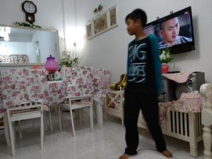 a young boy standing in a living room watching a tv at Anis Homestay Kuala Perlis in Kuala Perlis