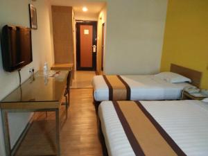 a hotel room with two beds and a flat screen tv at Tang Dynasty Lodge Tuaran in Tuaran