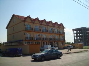 un gran edificio con coches aparcados delante en Hotel Principal, en Costinesti