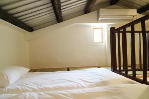 a bedroom with a white bed and a window at Through A Path in Tainan