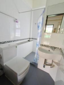 a white bathroom with a toilet and a sink at Moon Fox CaféInn Art & Gallery in Ubon Ratchathani