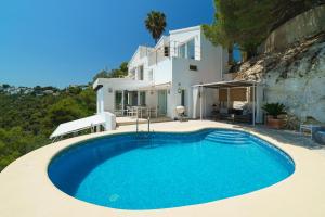 a swimming pool in front of a house at Villa Bombon in Jávea