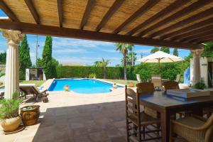 un patio con mesa, sombrilla y piscina en Villa Pinella, en Denia