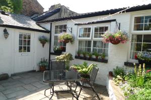 un patio con tavolo e sedie davanti a una casa di Courtyard Cottage a Knaresborough