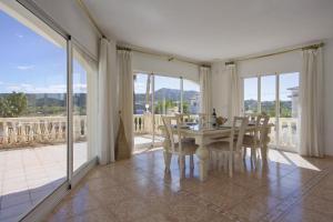 a dining room with a table and chairs and windows at Villa Cora in Jávea