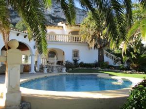 a swimming pool in front of a house with palm trees at Villa Lau in Denia