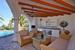 an outdoor living room with a kitchen and a pool at Villa Lau in Denia