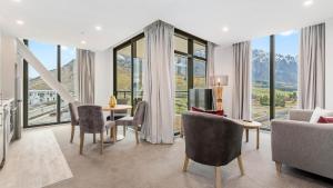 a living room with a table and chairs and windows at Remarkables Garden Apartment 305 in Queenstown
