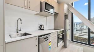 a kitchen with white appliances and a large window at Remarkables Garden Apartment 305 in Queenstown