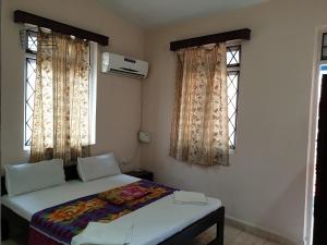 a bedroom with a bed and two windows at Bijou Guest House in Baga