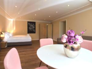 Pokój ze stołem, różowymi krzesłami i łóżkiem w obiekcie Amaroo - Apartments Potsdam “Alexandrowka” w Poczdamie