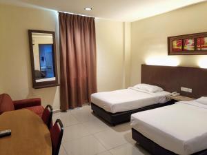 a hotel room with two beds and a table at Hotel Centre Point Tampin in Melaka
