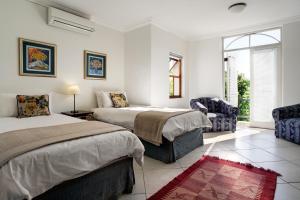 a bedroom with two beds and a chair at The Stellenbosch Hotel in Stellenbosch