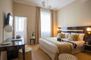 una camera d'albergo con un grande letto e una scrivania di Hotel Carlton a Beaulieu-sur-Mer
