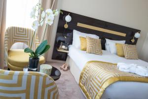 a bedroom with two beds and a chair at Hotel Carlton in Beaulieu-sur-Mer