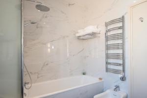 a white bathroom with a tub and a sink at Hotel Carlton in Beaulieu-sur-Mer
