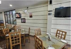a restaurant with tables and chairs and a flat screen tv at Hotel Landmark in Haridwār