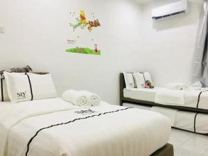 two beds in a room with white walls at SLV Small Luxury Villa - Villa B in Malacca
