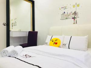 a bedroom with a white bed with a smiley face pillow at SLV Small Luxury Villa - Villa B in Malacca