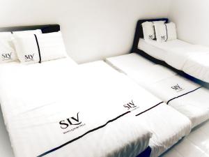 two beds in a room with white sheets and pillows at SLV Small Luxury Villa - Villa B in Malacca