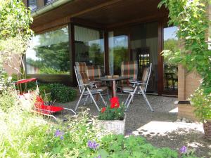 a patio with chairs and a table and some flowers at Ferienhaus Luhetalblick Prescher in Bispingen