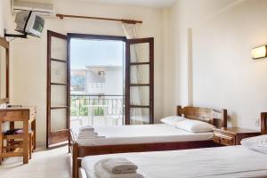 Zimmer mit 2 Betten und einem Fenster mit Balkon in der Unterkunft Aigaio in Kriopigi