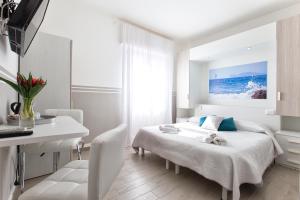 a white bedroom with a bed and a desk at Alguest in Alghero +34 photos