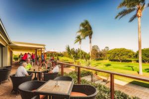 un grupo de personas sentadas en un restaurante con un campo de golf en Fairway Village @ Windaroo Lakes Golf Club en Windaroo