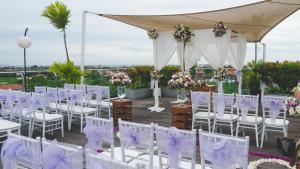 a set up for a wedding with white chairs and purple flowers at Hotel Daun Bali Seminyak in Seminyak