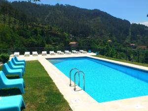 uma piscina com espreguiçadeiras ao lado de uma montanha em Hotel Lagoa Azul do Geres no Gerês