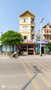 un hombre en una motocicleta por una calle al lado de un edificio en Nhà nghỉ FAMY, en Móng Cái
