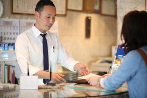 un hombre con corbata parado en un mostrador con una mujer en Hotel Yokosuka, en Yokosuka