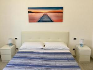 a bedroom with a bed with two night stands and a painting on the wall at Elite19 Apartment in Bocca di Magra