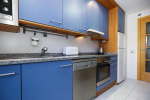 a kitchen with blue cabinets and a sink at Maldivas Planet Costa Dorada in La Pineda